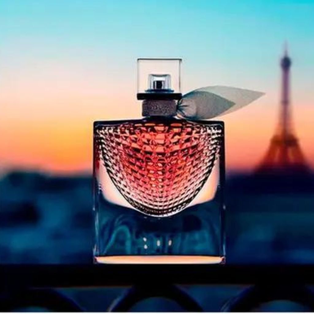 Perfume La Vie Est Belle L´´Eclat. A imagem traz o perfume em destaque com a torre Eiffel ao fundo.