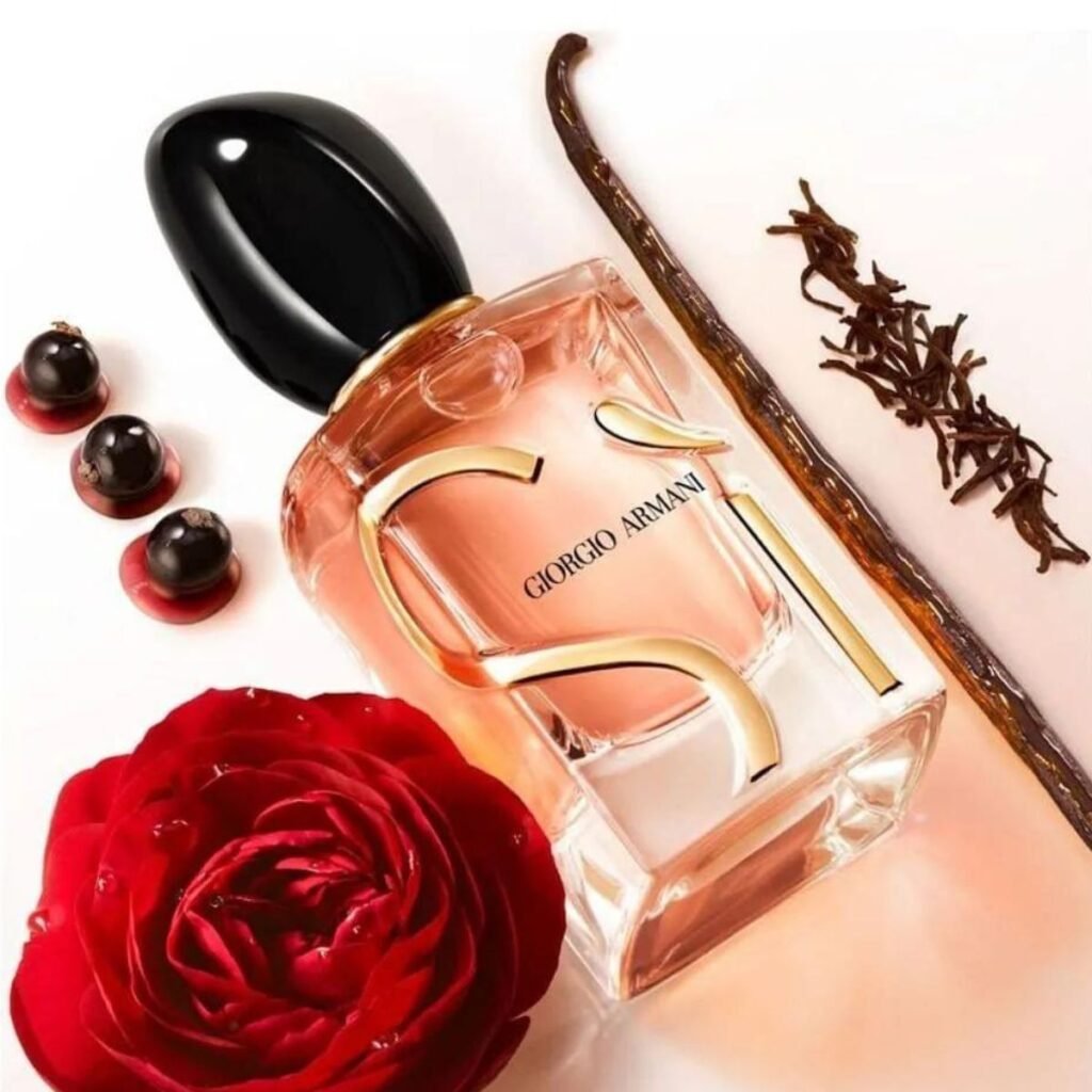 Perfume e desejo. A imagem mostra um vidro do perfume Giorgio Armani Si tombado sobre uma mesa ao lado de uma rosa e mais alguns objetos.