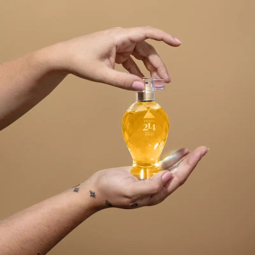 A imagem mostra o perfume Botica 214 nas mãos de uma mulher.