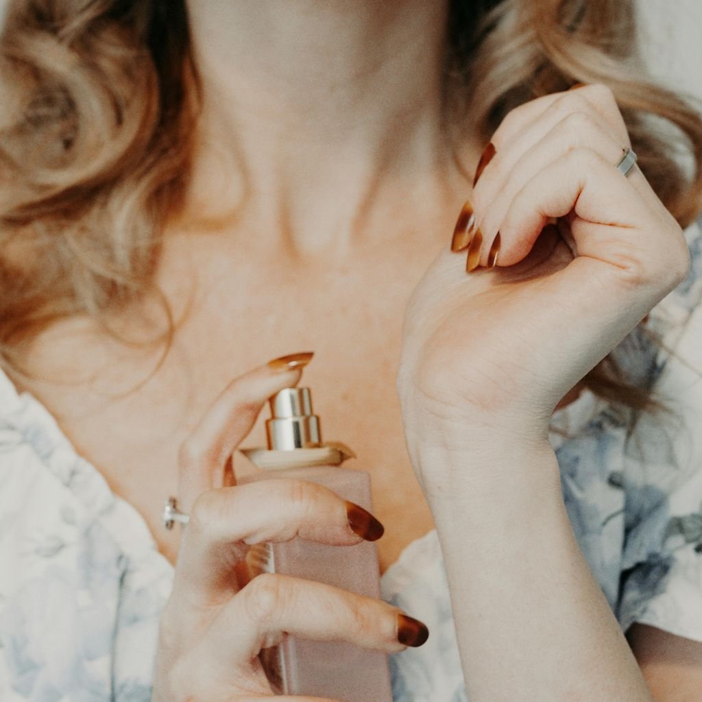 Mulher espirrando perfume no pulso.